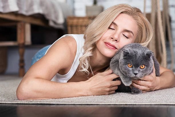 Beautiful blond lady with closed eyes lying on floor in bedroom cat